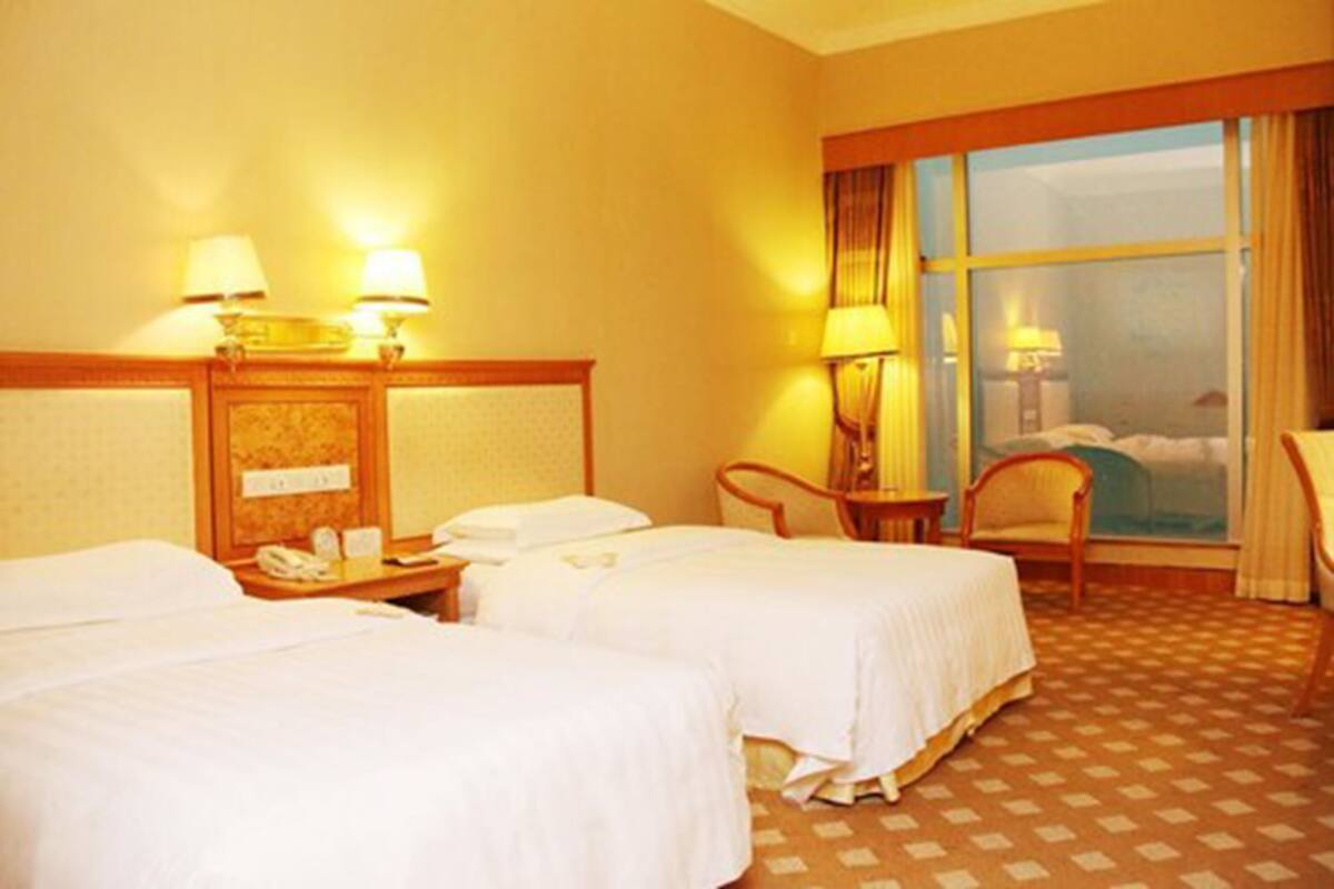 A hotel room with two beds, a desk with a telephone, and a chair.