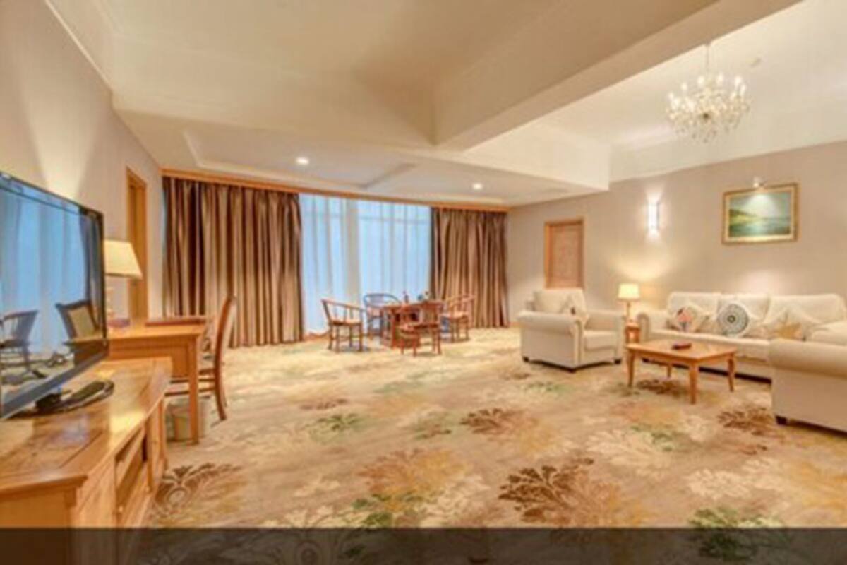 A spacious living room with a sofa set, a coffee table, a TV, and a dining area with chairs and a table.