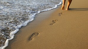 Una playa arenosa con huellas que se adentran en el agua.