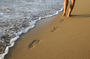 A sandy beach with footprints leading into the water.