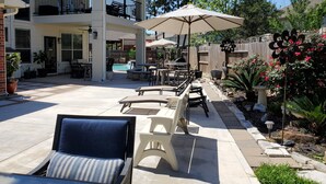 A covered patio area with outdoor furniture, a pool, and a wooden fence. -  The Oasis  w/Private Pool & Spa (Houston)