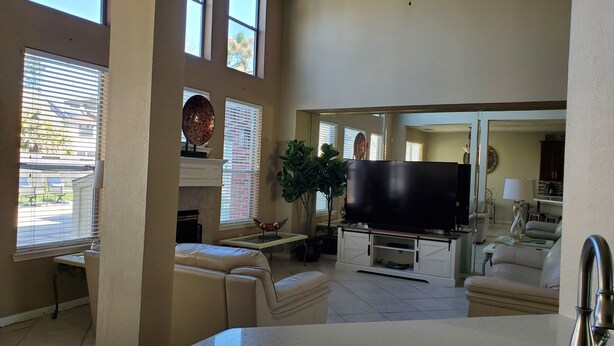 A spacious living room with a large flat-screen TV, a ceiling fan, and a dining area with a kitchen in the background. -  The Oasis  w/Private Pool & Spa (Houston)