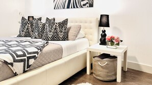 A bedroom with a bed, pillows, a nightstand, a lamp, and a wall art piece. - Downtown Suite in Cap Hill ! (Denver)