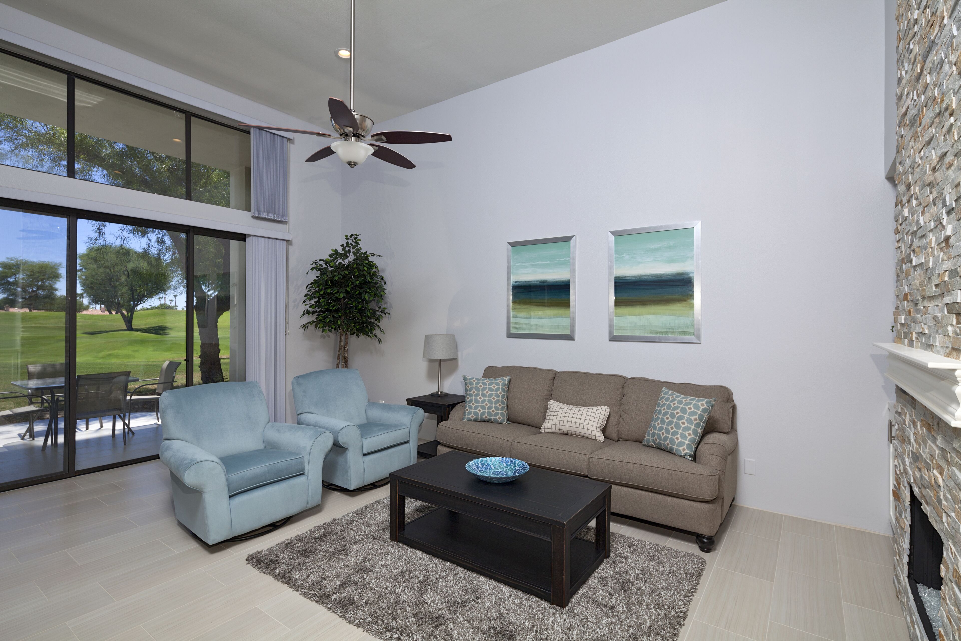 A modern living room with a sofa, two armchairs, a coffee table, and a fireplace.
