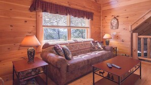 A cozy log cabin interior with a sofa, two lamps, and a table. - New Arcade 2-Pools 1 Pool YR RD ,Hot Tub,Mini Golf,FREE WIFI,Game Room (Pigeon Forge)