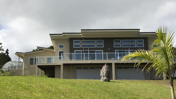 Une maison moderne à deux étages, dotée d’un toit plat, de grandes fenêtres et d’un patio couvert.