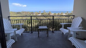 A balcony with white Adirondack chairs and a small table, overlooking a beach and ocean. - Spectacular Ocean Front Amelia Island Plantation, Breathtaking Ocean View  (Fernandina Beach)