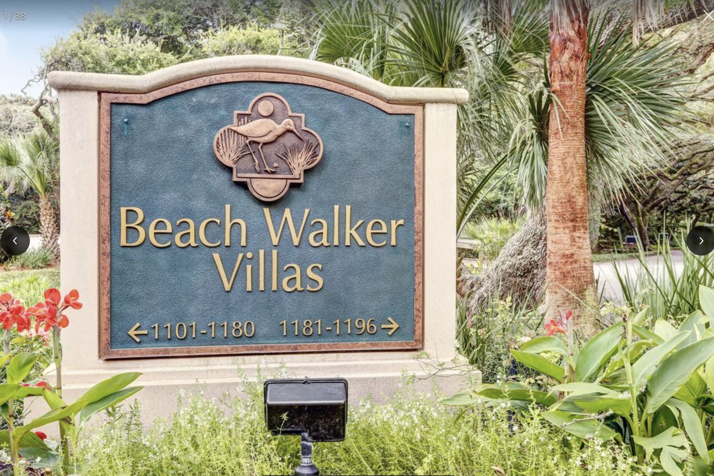 A sign for Beach Walker Villas with directional arrows and phone numbers.