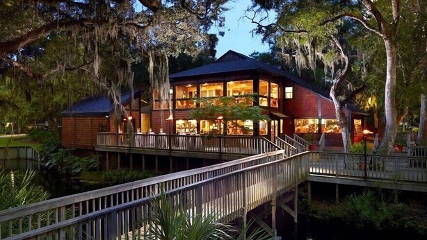 A two-story wooden house with a covered porch, surrounded by trees and a small pond. - Spectacular Ocean Front Amelia Island Plantation, Breathtaking Ocean View  (Fernandina Beach)