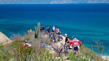 A group of cyclists on a coastal path with a view of the ocean.
