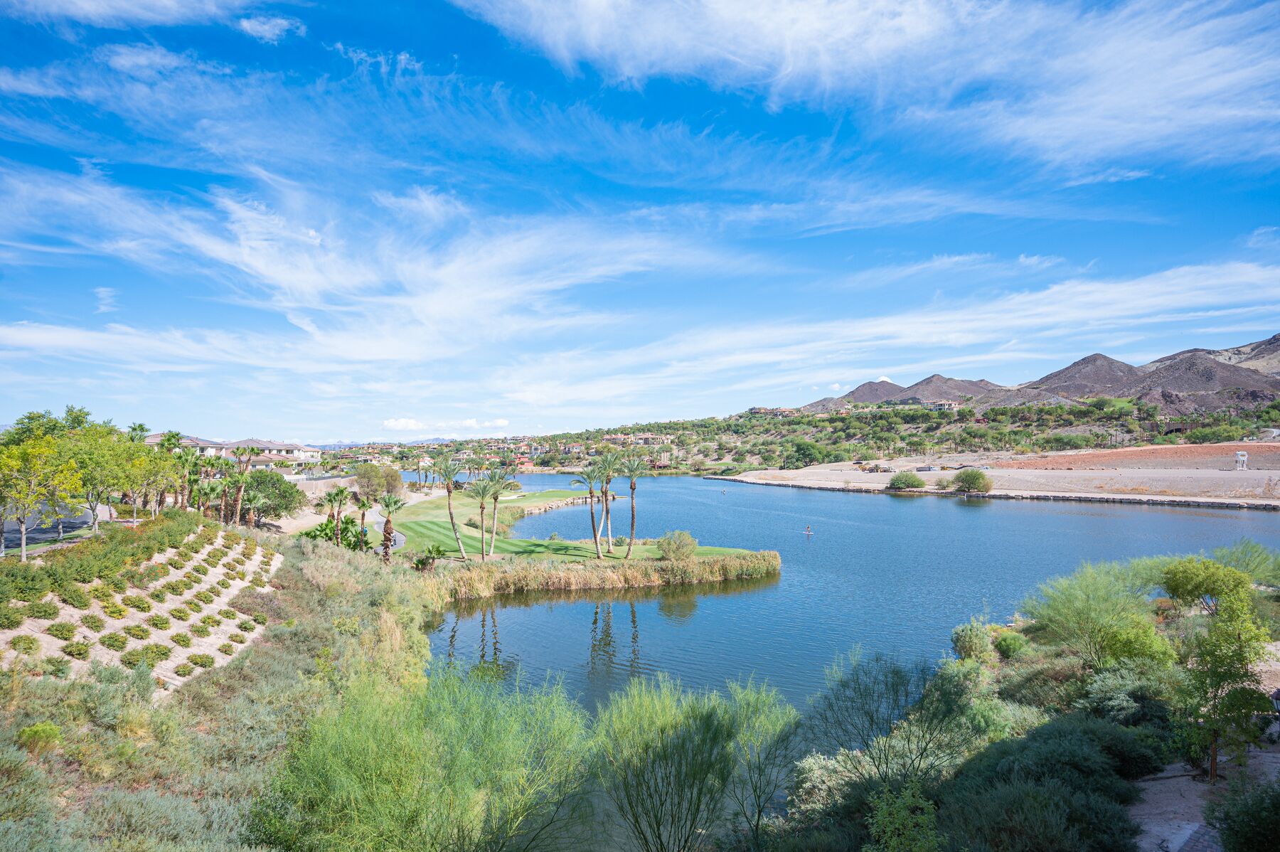A golf course with a lake, mountains, and a clear sky.