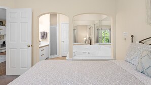 A bedroom with a bed, a bathroom with a bathtub, and a view of the outdoors. - Golf View Resort Condo | No Stairs + Pools & Perks (Branson)