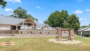 A building with a stone facade, a covered porch, and a sign indicating a golf club and pro shop. - Golf View Resort Condo | No Stairs + Pools & Perks (Branson)