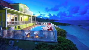 Een modern huis met een zwembad, een balkon en uitzicht op het strand.