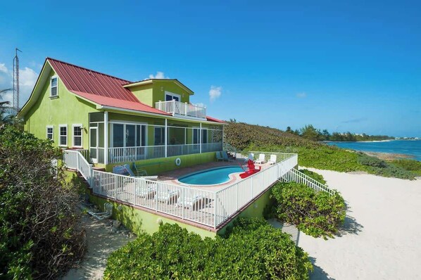 Une maison à deux étages avec un toit rouge, une piscine et une clôture blanche.