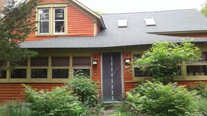Une maison en bois rouge avec une porte, des fenêtres et un petit porche de couleur grise.