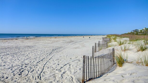 Une plage de sable avec une clôture en bois et des dunes.
