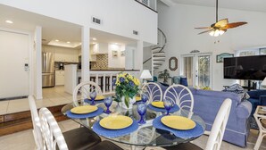 Un coin repas avec une table en verre, des chaises et des assiettes jaunes.