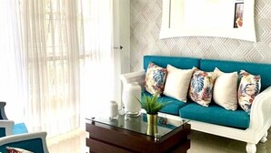 Ein Wohnzimmer mit einem blauen Sofa, einem weißen Sessel, einem Couchtisch und einer Kronleuchter.