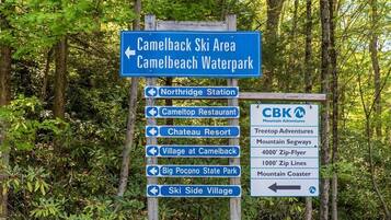 Een richtingwijzer met meerdere pijlen die naar verschillende bestemmingen wijzen, zoals Camelback Ski Area, Camelback Waterpark, Northridge Station, Cameltop Restaurant, Chateau Resort, Village at Camelback, Big Pocono State Park en Ski Side Village.
