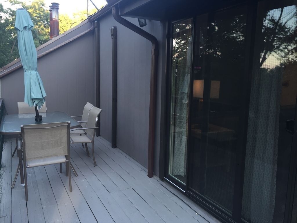 Une terrasse couverte avec une table et des chaises, une porte-fenêtre coulissante et une cheminée.