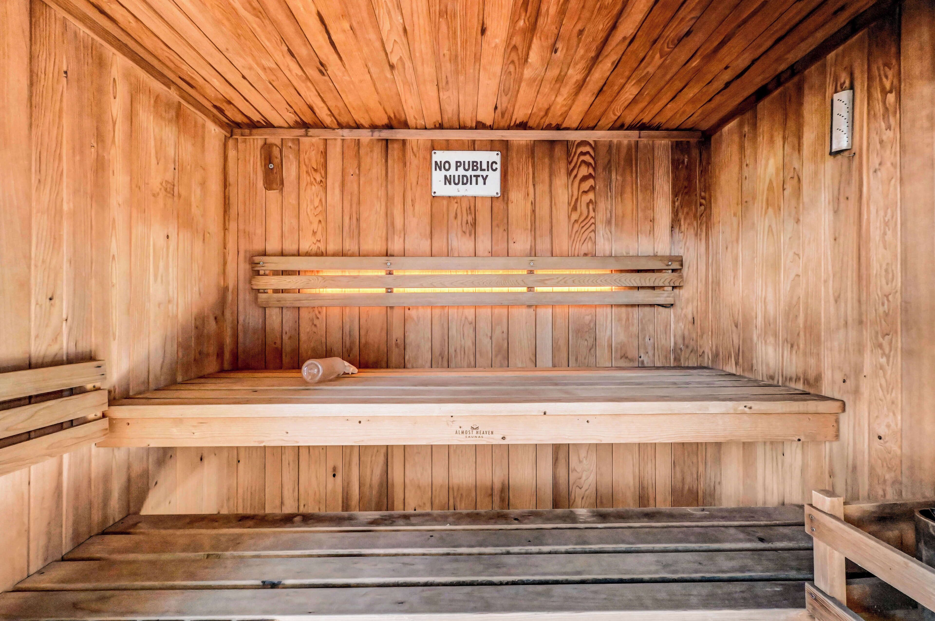 A wooden sauna with benches and a sign stating "NO PUBLIC NUDITY".