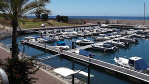 Un port de plaisance où sont amarrés de nombreux bateaux, une jetée en bois et une vue dégagée sur l’océan.