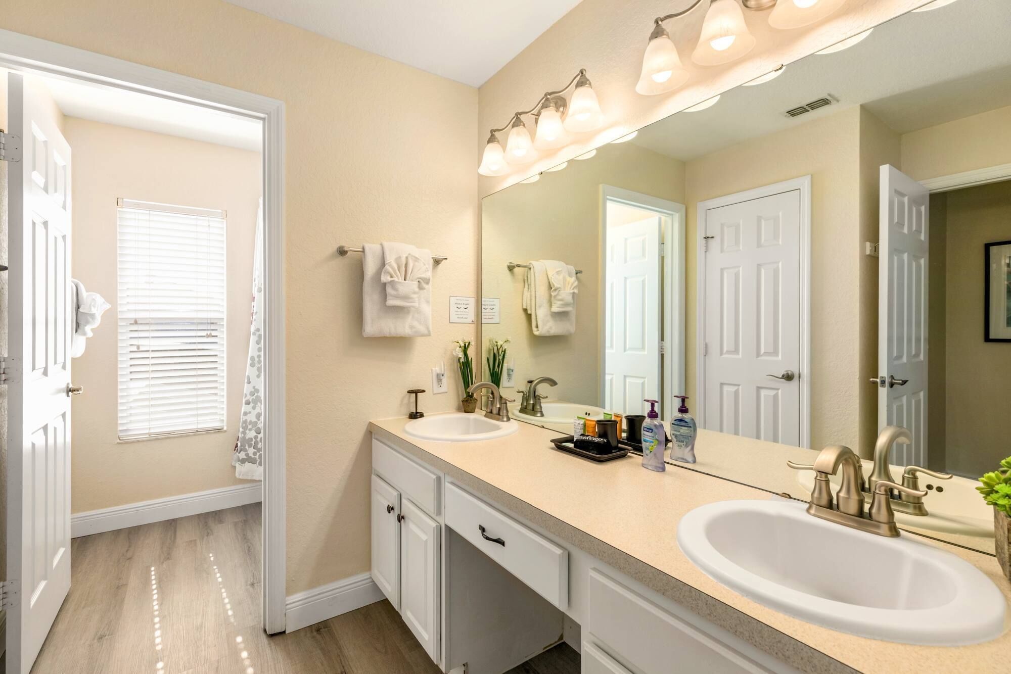 A bathroom with two sinks, a large mirror, and a shower.