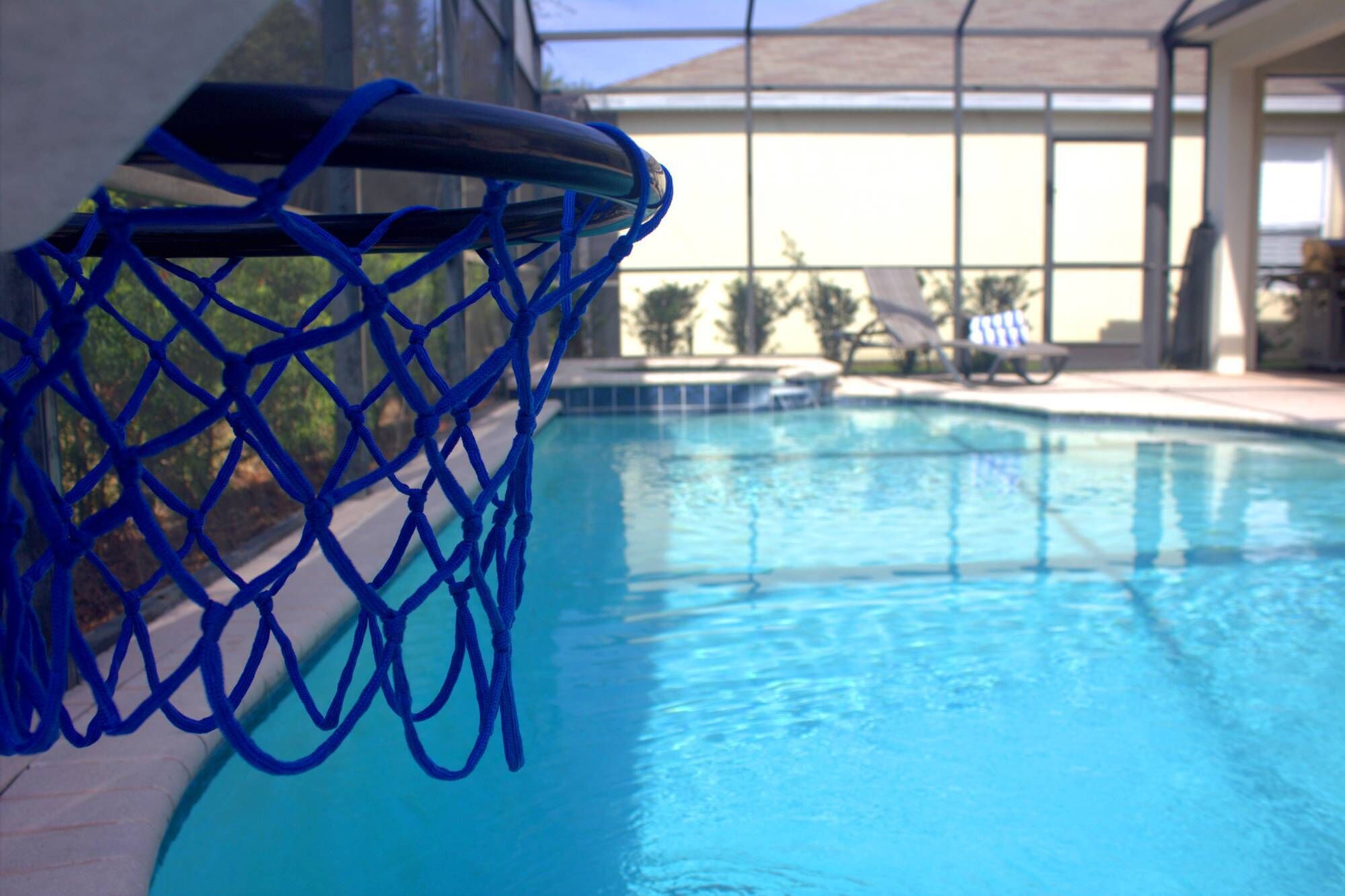 Une piscine avec un panier de basketball bleu, muni d’un filet.