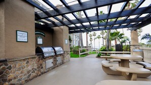 An outdoor barbecue area with stone walls and a pergola. - OCEANFRONT White Water Views Unit E-100  SEASONAL RATES AVAILABLE PLEASE INQUIRE (Oceanside)