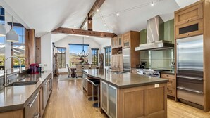 Una cocina amplia con armarios de madera, electrodomésticos de acero inoxidable y una isla grande con taburetes.