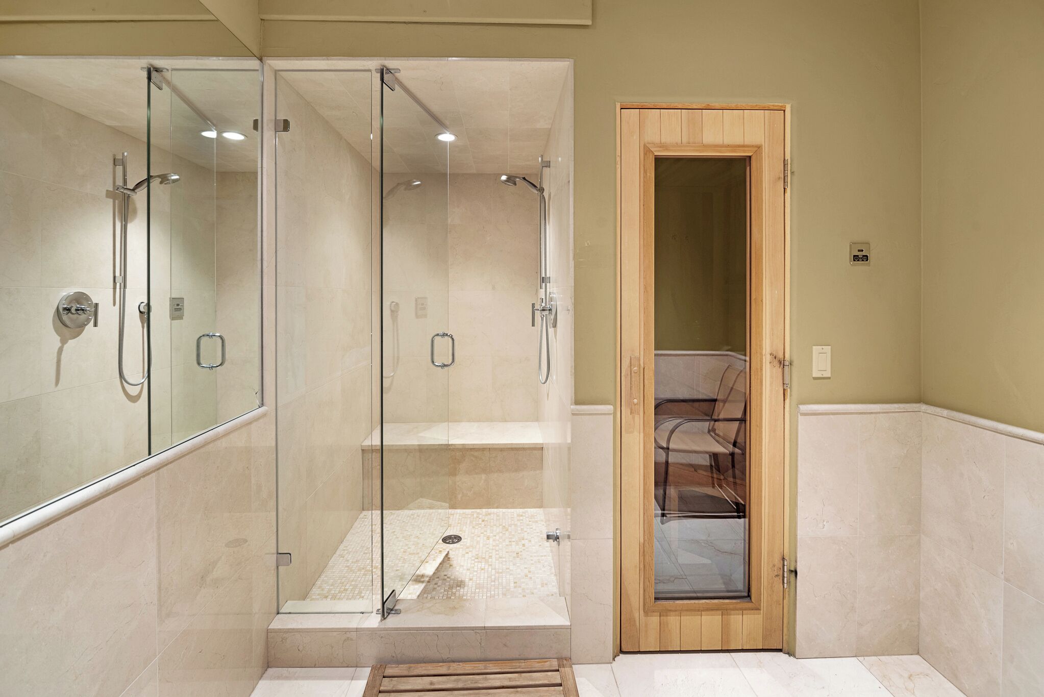 Une salle de bain moderne avec une douche à parois de verre, une porte en bois et un sol carrelé.