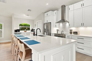 Una cocina moderna con armarios blancos, una isla central y un refrigerador de acero inoxidable.