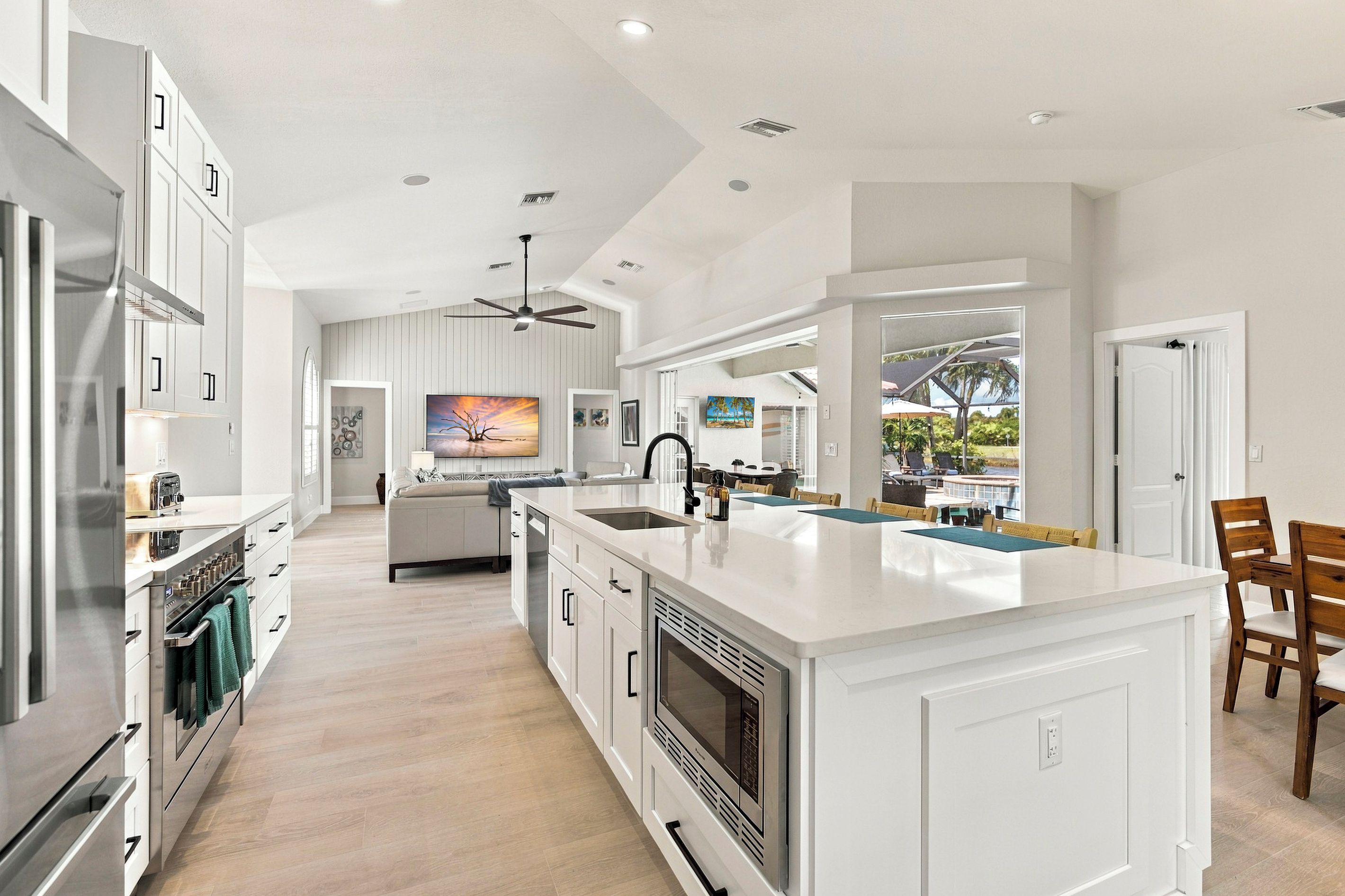 A modern kitchen with a large island, built-in appliances, and a dining area with a view.