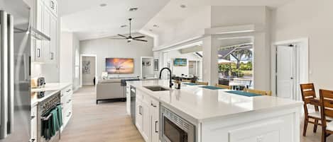 A modern kitchen with a large island, built-in appliances, and a dining area with a view.