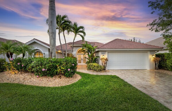 A residential house with a garage, palm trees, and a well-maintained lawn. - "Boho on the Canal" - Pool/Spa • 3 Kings • Renovated (Napels)