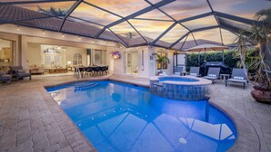 Una piscina con jacuzzi, sillas de descanso y un área de terraza cubierta.