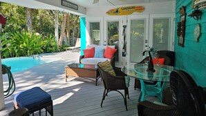 A covered outdoor area with a pool, seating, and a fan. - Newly Renovated Island Pool Home
 (Captiva)