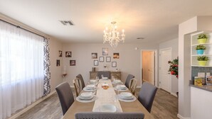 A dining room with a long table set for six, surrounded by chairs, a chandelier, and framed pictures on the wall. - Scottsdale 4BR – Heated Pool, Putting Green, 5 Min to Old Town (Scottsdale)