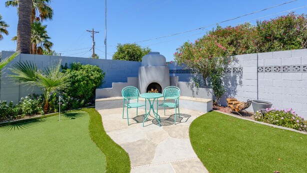 A patio with a stone fire pit, two green chairs, and a small table. - Scottsdale 4BR – Heated Pool, Putting Green, 5 Min to Old Town (Scottsdale)