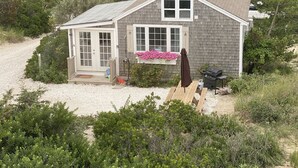 A single-story house with a front porch, a small deck, and a barbecue grill. - Cottage is on a PRIVATE BEACH shared between two houses.  (East Sandwich)