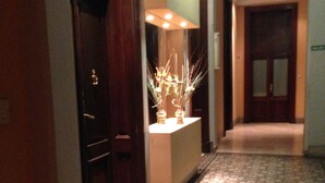 A hallway with patterned flooring, a reception desk with a vase of flowers, and a door with a sign above it. - Superb Central Location! SPECIAL OFFER (Montserrat)