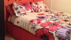 A bed with a floral bedspread, two wall-mounted lamps, and a pop art painting on the wall. - Superb Central Location! SPECIAL OFFER (Montserrat)