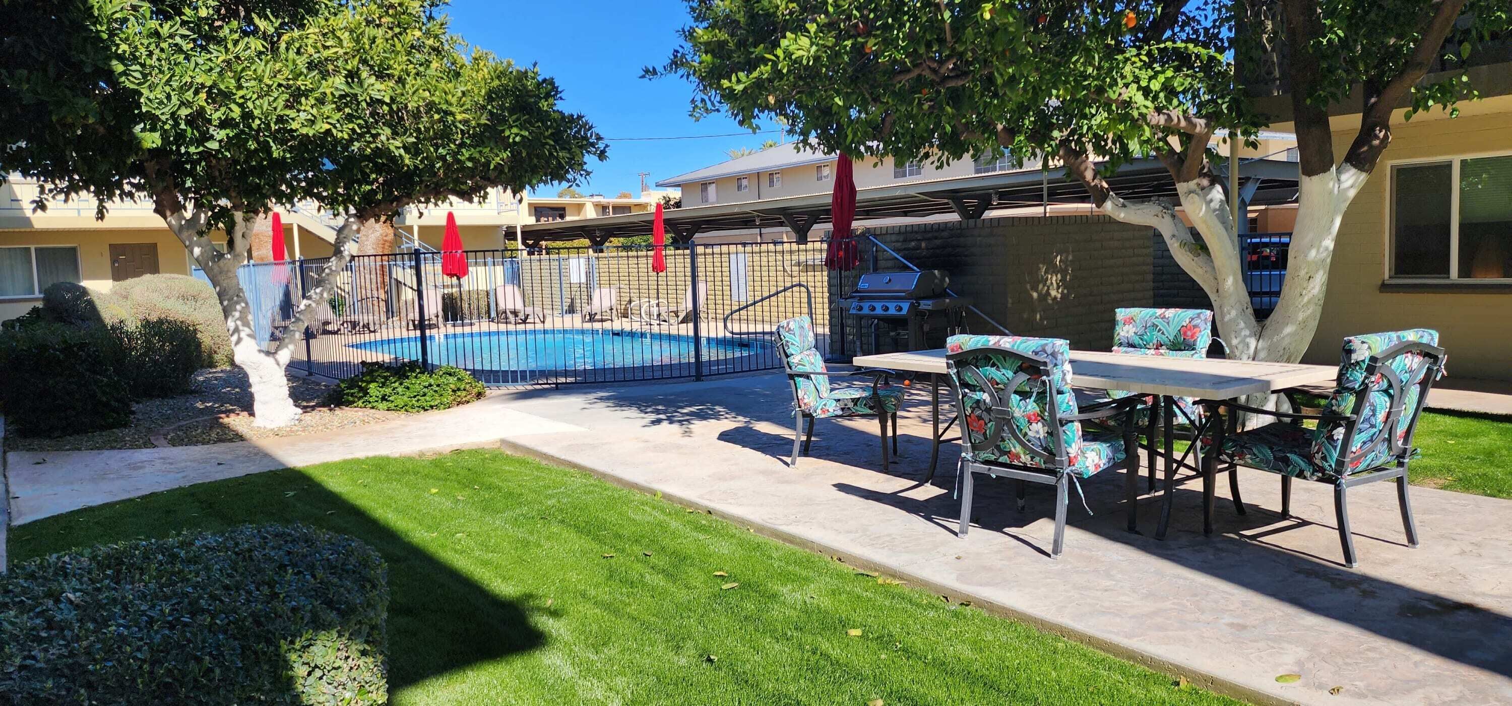 Un patio trasero con piscina, muebles de jardín y una parrilla.
