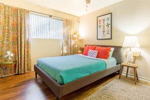 Une chambre à coucher avec un lit, des rideaux, une lampe de chevet, une horloge murale et un tableau encadré.