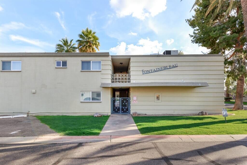 A two-story building with a flat facade, a gated entrance, and a small balcony.