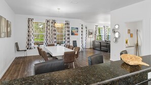 A modern kitchen with a granite countertop, a dining area with a white table and brown chairs, and a view of the outdoors through large windows. - 20 yrds to water! BBQ, Scalloping And Manatee Watching, Families welcome!  (Homosassa)