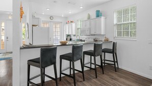 A modern kitchen with a central island, bar stools, white cabinetry, and a window with blinds. - 20 yrds to water! BBQ, Scalloping And Manatee Watching, Families welcome!  (Homosassa)