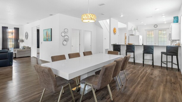 A modern kitchen with a white countertop, a hanging light fixture, and a dining area with a white table and brown chairs. - 20 yrds to water! BBQ, Scalloping And Manatee Watching, Families welcome!  (Homosassa)