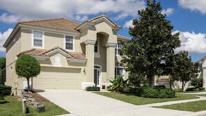 A two-story house with a beige facade, a tiled roof, and a front garage. - 🏰 Magical 6-Bed Family Villa ✨[FREE Heated Pool, Spa & BBQ] 5 Mins to Disney 🎢 (Kissimmee)